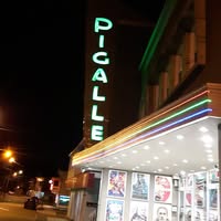 La façade du Cinéma Pigalle et son enseigne au néon, rue Notre-Dame, le soir.